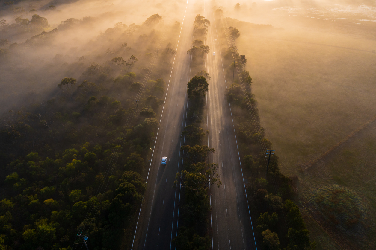 Traffic passing along a foggy highway on sunrise in Victoria, Australia.